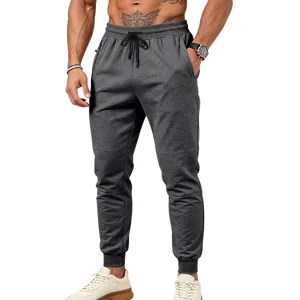 Vista dettagliata dei pantaloni tuta grigio scuro da uomo con coulisse e tasche con zip.