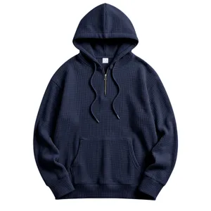 Detailed view of a dark blue waffle knit quarter-zip hoodie featuring a kangaroo pocket.
