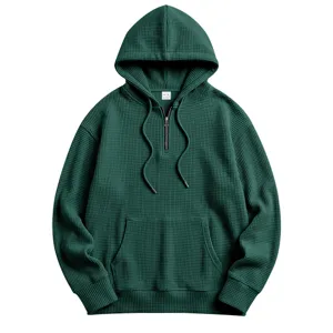 Close-up detail of dark green waffle knit half zip hoodie with hood and front pocket texture