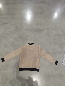 Detailed view of men's faux suede bomber jacket featuring black ribbed collar and cuffs.