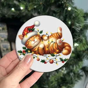 Vista cercana de un posavasos redondo con lindo gato navideño, decoración festiva.