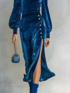 Close-up product detail of luxury blue velvet long sleeve dress featuring side slit and gold buttons.