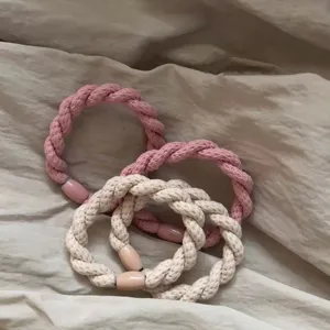 Close-up detail of braided hair ties with decorative beads, soft fabric texture, stylish accessory.