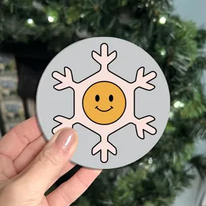 Cute round car coaster with pink snowflake and smiley face design, non-slip rubber mat.