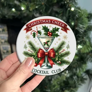 Close-up shot of a festive round Christmas cocktail themed coaster with holiday holly and bow.
