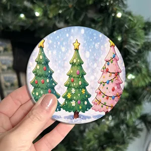 Close up view of a round ceramic Christmas coaster featuring cute tree designs and snow.