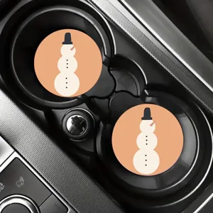 Detailed shot of cute cartoon snowman car coasters placed inside a vehicle cup holder interior.
