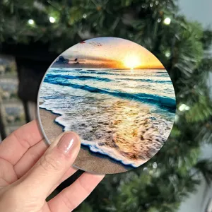 Dessous de verre rond absorbant en pierre avec vue sur le coucher de soleil à la plage.