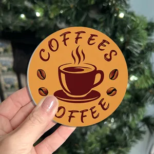Closeup detail of the round coffee cup coaster featuring cute cup and coffee bean graphic print.