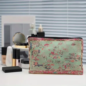 Nahaufnahme des Kosmetiktäschchens im Vintagestil mit Blumenmuster und feiner Stoffstruktur.