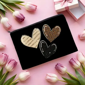 Détail de trousse de maquillage en toile noire avec fermeture éclair et motifs de cœur.