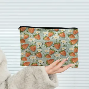 Close-up detail of a cute strawberry and floral print cosmetic pouch with black zipper.