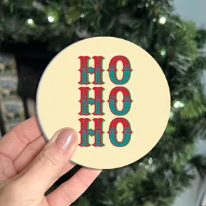 Close-up detail of festive round car drink coaster with red and green Ho Ho Ho holiday pattern.