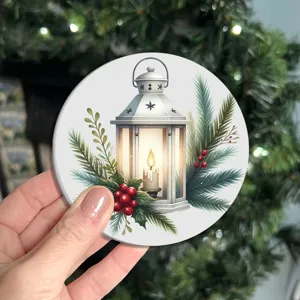 Gros plan d'un dessous de verre de Noël rond avec une lanterne blanche et des branches de pin.