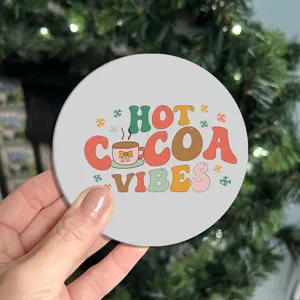 Close-up detail shot of a round car cup coaster featuring hot cocoa vibes holiday print.