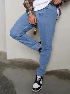 Primo piano di jeans regular fit azzurri abbinati a camicia casual e scarpe da ginnastica.