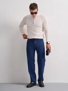 Men's classic straight-fit blue jeans styled with half-zip sweater and leather shoes in detail.