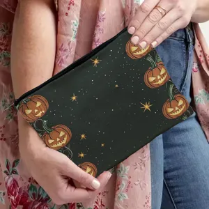 Halloween pumpkin print makeup pouch detail view, black zippered cosmetic bag held by hand.