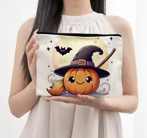 Close-up detail of a cute Halloween pumpkin witch hat print canvas makeup pouch held by hand.