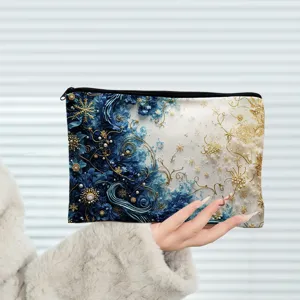 Détail de pochette cosmétique à fermeture éclair en toile motif artistique bleu et or.