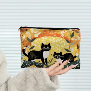 Detail of black cat cosmetic pouch featuring autumn leaf print and secure zipper closure.