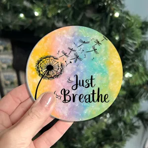Gros plan détaillé d'un sous-verre rond en silicone coloré avec un motif de pissenlit et texte.