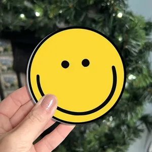 Sottobicchiere tondo in silicone giallo con un simpatico viso sorridente nero.