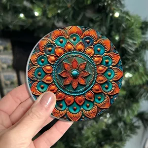 Detail shot of round mandala pattern coaster with vibrant orange and turquoise floral design.
