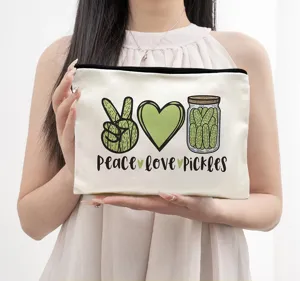 Detail view of a white canvas cosmetic bag with cute pickle graphics and zipper closure.