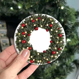 Primo piano della tovaglietta rotonda di Natale con design a ghirlanda festiva e palline rosse.