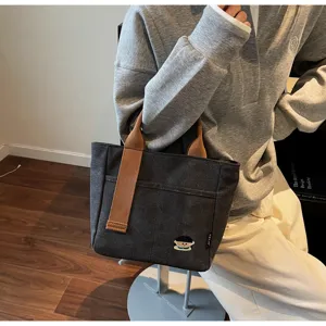 Detailed view of the dark grey canvas tote bag with brown handles and cute embroidery.