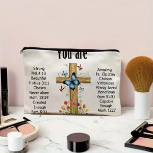 Detalle de bolsa de maquillaje de lona con cruz y mariposa, ideal para guardar cosméticos.