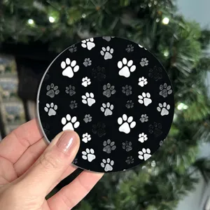 Round black absorbent coaster with white paw print pattern for home office desk decor.
