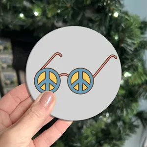 Close-up detail of a round silicone drink coaster featuring a retro peace sign glasses graphic.