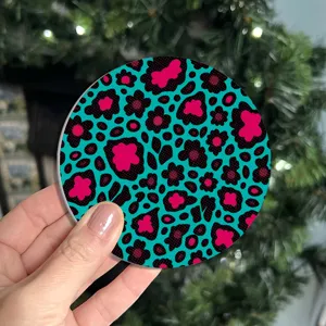 Round silicone car coaster with vibrant blue pink and black leopard heart print for table use.