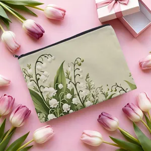 Detailed view of the fabric cosmetic pouch featuring lily of the valley botanical print and secure zipper.