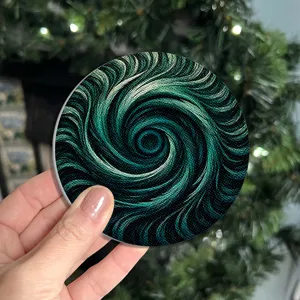 Close-up of a round decorative coaster with striking green and black vortex swirl pattern.