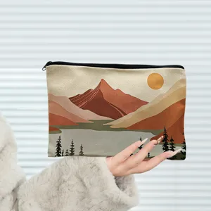 Gros plan d'une trousse de maquillage en toile avec imprimé paysage de montagne et fermeture.