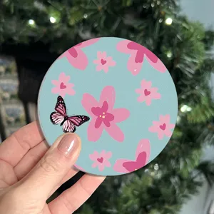 Close-up detail of a round blue coaster featuring a charming pink floral and butterfly pattern.