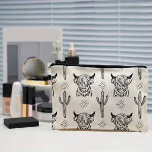 Canvas cosmetic bag showing close-up of cute Highland cow and cactus graphic design.