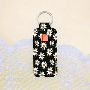 Floral lipstick holder keychain detail view, black daisy pattern lip balm pouch with metal ring.