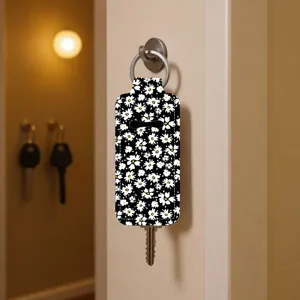 Close-up detail of a floral print lipstick cover keychain hanging on the wall hook.