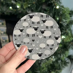 Close-up view of a cute cartoon sheep pattern round coaster with grey background and little hearts.