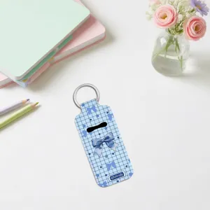 Blue plaid bow print lipstick holder keychain with metal ring displayed on clean desk.