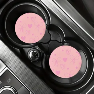 Close-up of pink car cup coaster with cute bow and heart pattern inside vehicle holder.