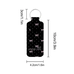 Close-up detail view of the black bow print neoprene lipstick holder keychain with clear sizing.