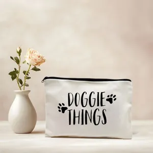 Canvas cosmetic bag detail showing black Doggie Things print and paw design on white fabric.