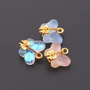 Close-up detail of colorful translucent butterfly pendants with gold flower charms for DIY jewelry.