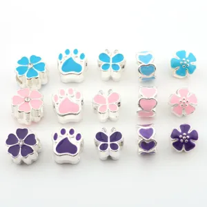 Close-up of colorful enamel flower and paw charm beads, silver tone DIY jewelry accessories.