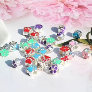 Closeup of colorful enamel alloy large hole beads, paw and flower charms for DIY jewelry making.